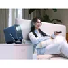 A woman is relaxing on a bed, holding a remote control and watching a projector. Produktbild-Vorschau