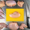 A collection of raw chicken pieces arranged around a yellow cutting board with a knife on the side. Produktbild-Vorschau