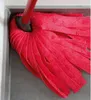 A close-up view of a red mop head with a red handle, positioned in a gray corner. Anteprima dell’immagine prodotto