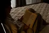 A person is reading a book while lying on a bed. Produktbild-Vorschau