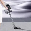 A person is using a cordless vacuum cleaner on a carpeted floor. Produktbild-Vorschau