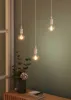 Three pendant lights hanging in a room with a green wall and a wooden table with a vase of flowers. Produktbild-Vorschau
