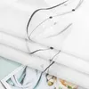 A close-up view of folded white fabric with a black embroidered pattern. Produktbild-Vorschau