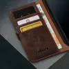 A close-up view of a brown leather wallet with cards and banknotes inserted, resting on a textured surface. Produktbild-Vorschau