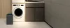 A laundry room scene with a washing machine, a dehumidifier, and cabinets. Produktbild-Vorschau