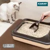 A cat is looking at a litter box while a hand is scooping it with a litter scoop. A mat is placed in front of the litter box. Produktbild-Vorschau