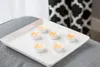Six tea lights on a white square tray, placed on a gray surface. Náhled obrázku produktu