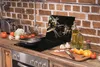 A kitchen counter with a stovetop, cooking utensils, and ingredients. Produktbild-Vorschau