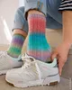 A person is putting on a pair of colorful knitted socks with sneakers. Produktbild-Vorschau