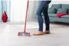A person is sweeping the floor with a red broom in a living room. Anteprima dell’immagine prodotto