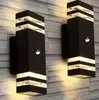 Two black outdoor wall lights mounted on a textured gray wall. Produktbild-Vorschau
