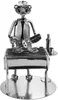 A metal figurine of a person grilling fish on a barbecue. Produktbild-Vorschau