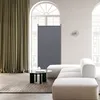 A modern living room with a large sectional sofa, a coffee table, and a room divider placed near a window with curtains. Anteprima dell’immagine prodotto