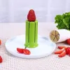 A strawberry is placed on top of a green slicer tool, with sliced tomatoes and strawberries on a white plate in front of it. A bunch of lettuce is in the background. Podgląd zdjęcia produktu