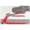A shoe is pressing down on a pair of pliers, which are holding a red pipe. The scene is set on a textured gray surface. Anteprima dell’immagine prodotto