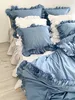 A neatly made bed with blue and white ruffled bedding. Podgląd zdjęcia produktu