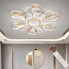 A modern ceiling light fixture with a flower-like design, mounted on a white ceiling. A remote control is shown in the foreground. Podgląd zdjęcia produktu