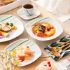 A table setting with plates of food, a cup of tea, and cutlery. Náhled obrázku produktu