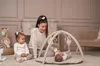 A mother and two children are playing on a play mat with a baby gym. Produktbild-Vorschau