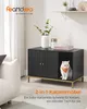 A cat is sitting inside a black cabinet with gold legs, which is presented as a piece of furniture in a living room setting. The cabinet has a compartment for the cat and a closed section with doors. Produktbild-Vorschau