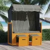 A beach chair with a striped canopy and cushions is set up on a wooden deck near a beach with palm trees. Voir les images du produit