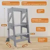 A grey wooden kitchen helper stool with text overlays indicating its features and dimensions. Produktbild-Vorschau