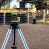 A man is using a laser leveler in an outdoor rural setting near a fence and water tank. Produktbild-Vorschau