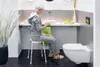 An elderly woman sits on a shower stool in a modern bathroom. Produktbild-Vorschau