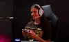 A young woman wearing a headset and holding a game controller, playing a video game. Produktbild-Vorschau