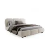 A modern upholstered bed with pillows and a blanket, presented on a white background. Produktbild-Vorschau