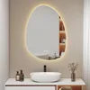 A modern bathroom vanity with a sink, faucet, and an illuminated, irregularly shaped mirror above it. Náhľad obrázku produktu