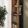 A tall, narrow bookshelf with wooden accents is filled with books and decorative items. A lush green plant is in the foreground, and sheer white curtains are visible in the background. Anteprima dell’immagine prodotto