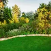 A lush garden with a manicured lawn and a wooden fence. Náhled obrázku produktu