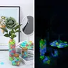A split image showing decorative glowing stones in jars and on a plate, both in daylight and in darkness. Produktbild-Vorschau
