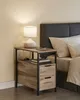 A bedside table with a lamp and books next to a bed. Produktbild-Vorschau
