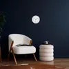 A clock on a wall above a chair and a stool. Náhľad obrázku produktu