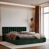 A plush green upholstered bed with a fluted headboard, set in a modern bedroom with neutral walls and large windows. Anteprima dell’immagine prodotto