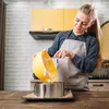 A woman is baking in a kitchen, pouring batter from a yellow bowl into a cake ring. Podgląd zdjęcia produktu