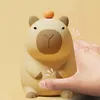 A hand is shown touching a cute, cartoonish capybara-shaped night light. Podgląd zdjęcia produktu