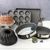 A collection of baking pans and a decorated cake are arranged on a white surface with a speckled gray background. Produktbild-Vorschau