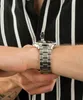 A close-up shot of a person's wrist wearing a silver watch. Podgląd zdjęcia produktu