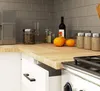 A kitchen counter with various items, including a coffee maker, jars, pumpkins, and a wine bottle. Produktbild-Vorschau