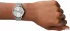 A close-up shot of a woman's wrist wearing a silver Armani Exchange watch. Voir les images du produit