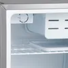 Close-up view of the interior of a mini-fridge, showing the temperature control dial, freezer compartment, and wire shelves. Voir les images du produit