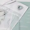 Close-up of a white sheer curtain with a gray embroidered wave pattern and a silver grommet, placed over a light green surface with text. Produktbild-Vorschau