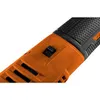 A close-up view of the orange and black body of a power tool, showing a black switch and ventilation slots. Podgląd zdjęcia produktu