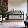 A shelf unit in a living room setting with plants and decorative items. Produktbild-Vorschau