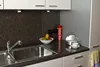 A kitchen counter with a sink, fruit bowl, and a fire extinguisher spray. Produktbild-Vorschau