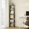 A tall, narrow bookshelf filled with books and binders stands next to a window with sheer curtains. A desk with a computer monitor, a coffee cup, and office supplies is visible to the right. Produktbild-Vorschau