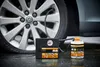 A car tire being inflated with a tire sealant kit on a wet surface. Produktbild-Vorschau